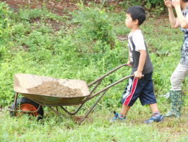 一輪車で土を運ぶ子供達